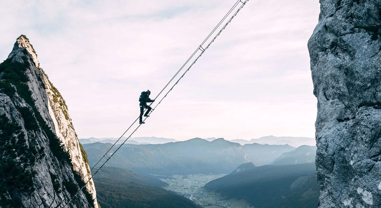 Man climbing a steep cliff representing determination and challenge