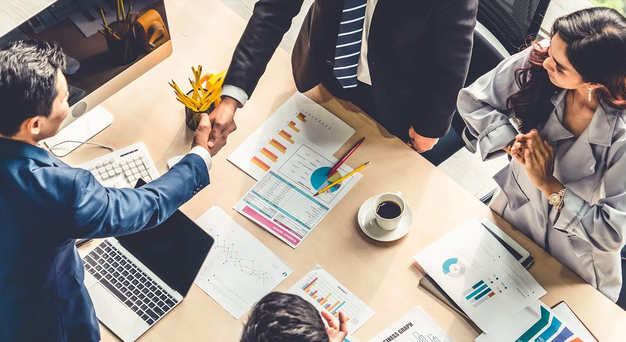 Partners shaking hands in agreement in a rounded table conference