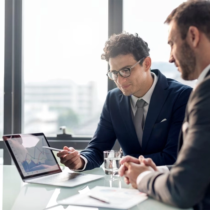 Two businessmen analyzing market data on a laptop