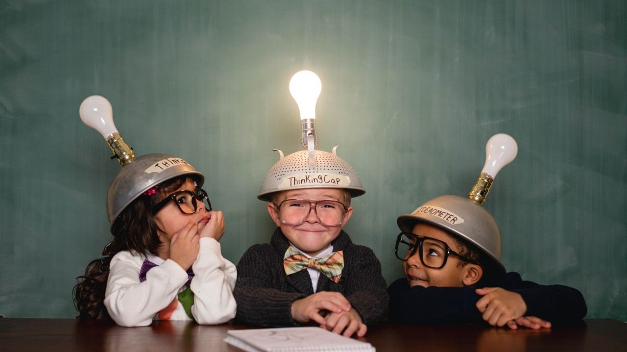 Young retro nerds and a boy with a bright idea, smiling and collaborating