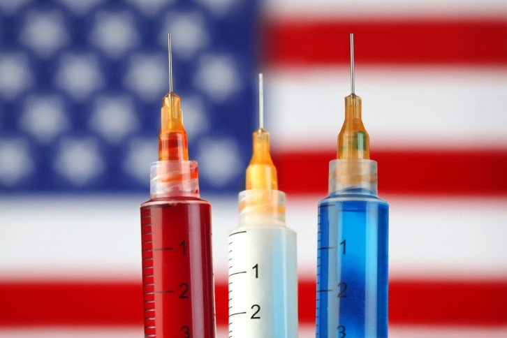 Red, white, and blue syringes arranged above the American flag background