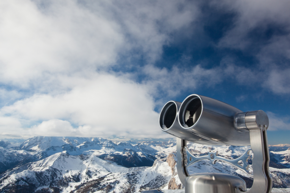 Coin-operated binoculars focused on snowy mountains symbolizing business outlook and future perspective